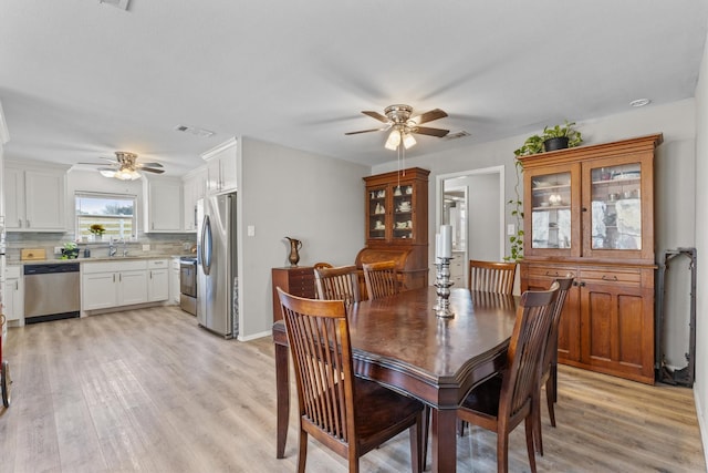 dining area with ceiling fan, light wood-type flooring, and sink