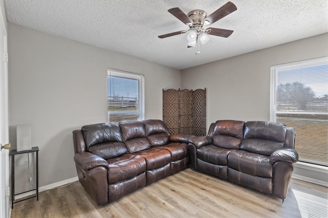 living room featuring ceiling fan, plenty of natural light, a textured ceiling, and light wood-type flooring