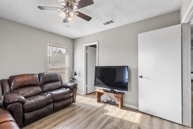 living room featuring a textured ceiling, ceiling fan, and light hardwood / wood-style floors