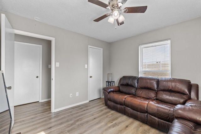 living room featuring ceiling fan, a textured ceiling, and light hardwood / wood-style flooring