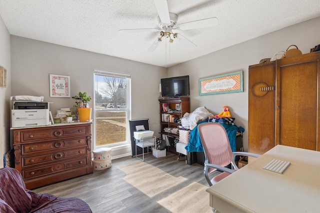 office area with light hardwood / wood-style floors, a textured ceiling, and ceiling fan