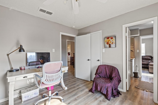 office space featuring light hardwood / wood-style floors, a textured ceiling, and ceiling fan