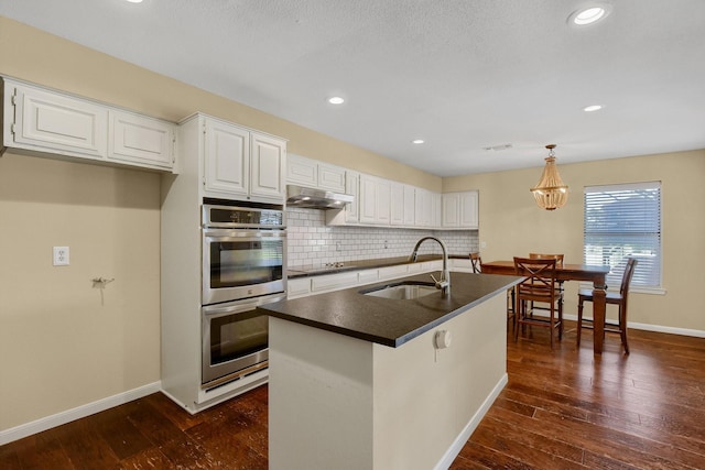 kitchen with hanging light fixtures, white cabinets, double oven, and sink