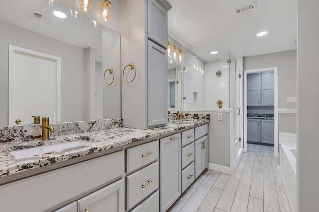 bathroom with vanity and shower with separate bathtub