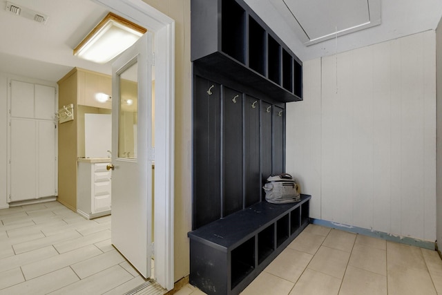 mudroom featuring light tile patterned floors and wooden walls