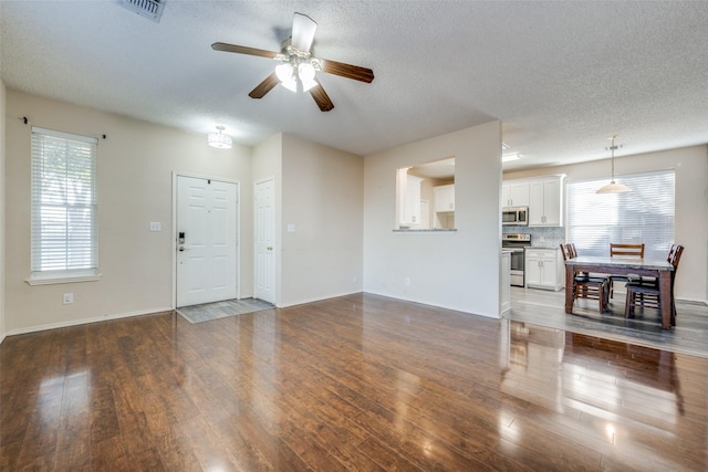 unfurnished living room featuring a textured ceiling, ceiling fan, and dark hardwood / wood-style floors