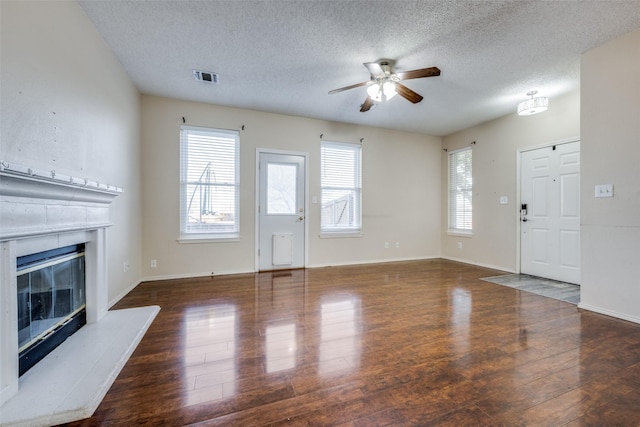 unfurnished living room with ceiling fan, a textured ceiling, and dark hardwood / wood-style floors