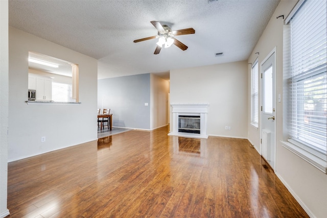 unfurnished living room with ceiling fan, a textured ceiling, and hardwood / wood-style flooring