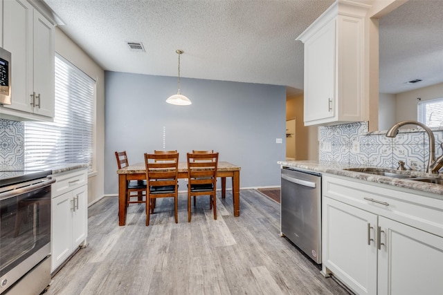 kitchen with light stone countertops, white cabinetry, stainless steel appliances, decorative backsplash, and sink