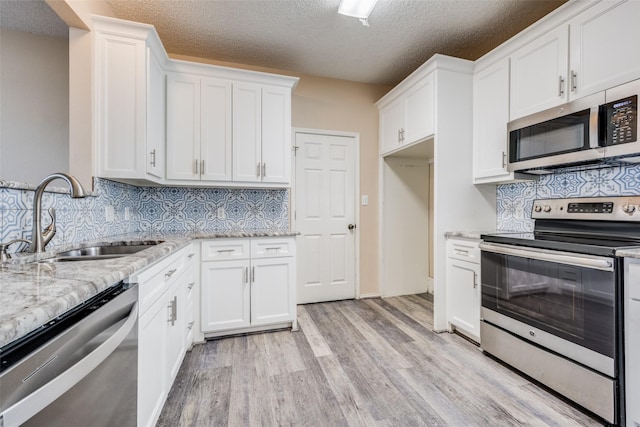 kitchen featuring decorative backsplash, sink, white cabinetry, and appliances with stainless steel finishes