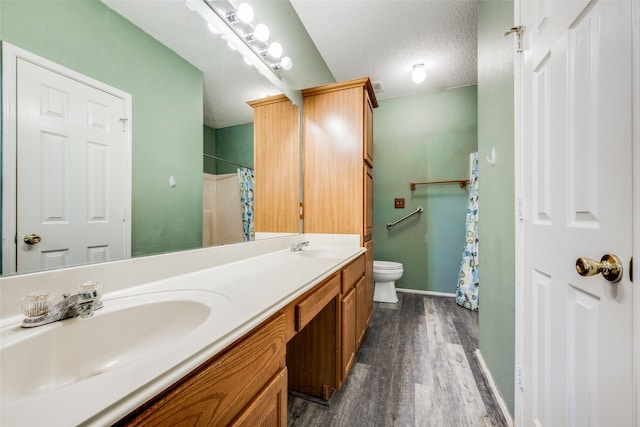 bathroom featuring curtained shower, a textured ceiling, hardwood / wood-style floors, vanity, and toilet