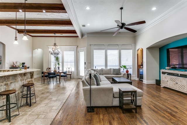 living room featuring ceiling fan with notable chandelier, ornamental molding, and beam ceiling