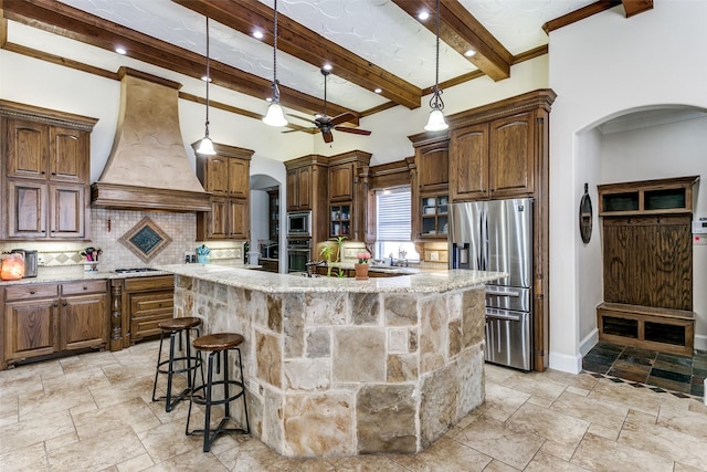 kitchen featuring custom range hood, stainless steel appliances, decorative backsplash, a center island with sink, and beam ceiling