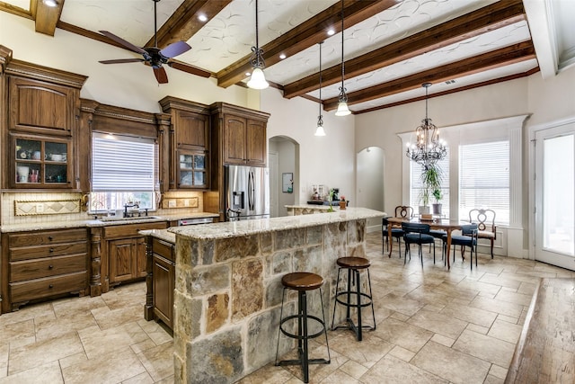 kitchen with a kitchen island, beamed ceiling, decorative backsplash, a kitchen breakfast bar, and stainless steel fridge with ice dispenser