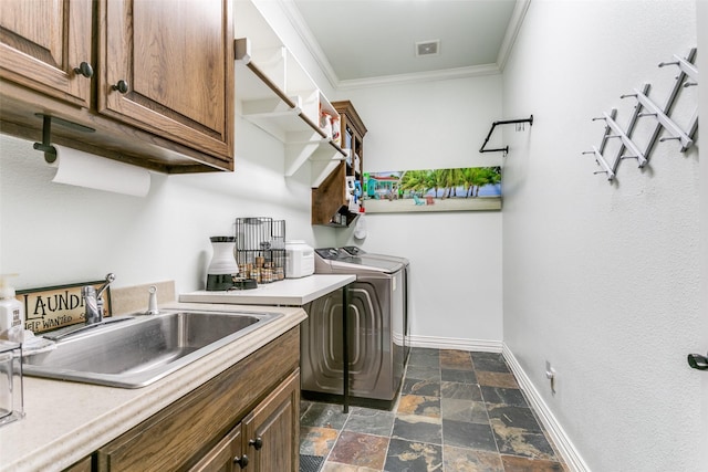 washroom featuring sink, crown molding, washing machine and clothes dryer, and cabinets