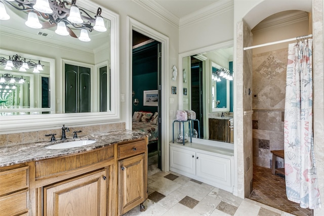 bathroom with ornamental molding, vanity, a tile shower, and an inviting chandelier