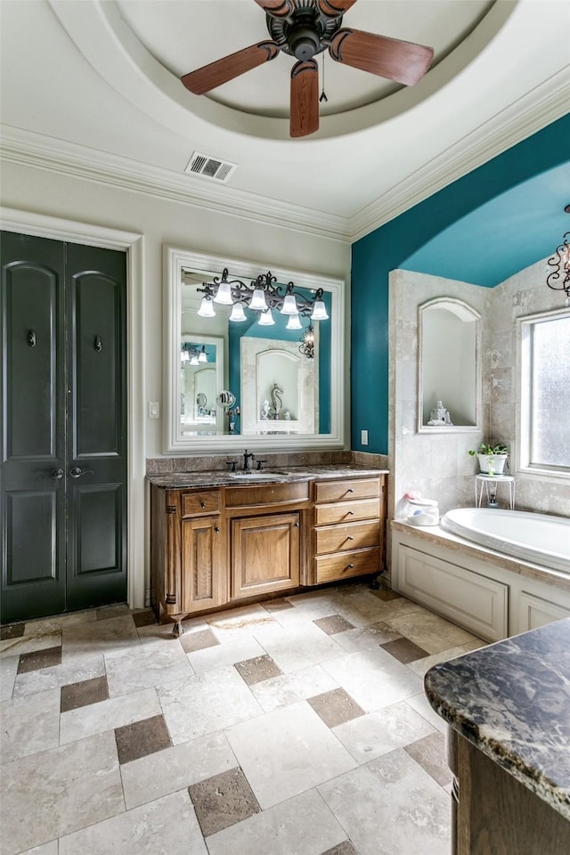 bathroom featuring vanity, a bathing tub, ornamental molding, and a tray ceiling