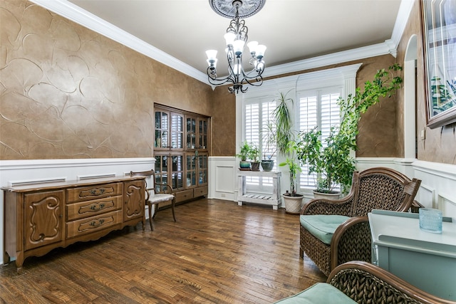 living area featuring dark wood-type flooring, ornamental molding, and an inviting chandelier