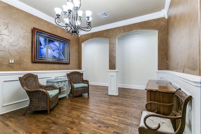 living area featuring dark wood-type flooring, crown molding, and a notable chandelier