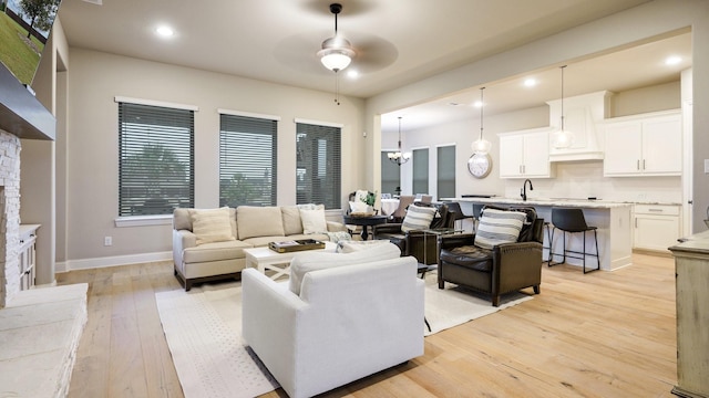 living room featuring light hardwood / wood-style floors and ceiling fan with notable chandelier