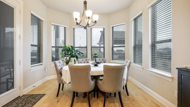 dining area with light wood-type flooring and an inviting chandelier