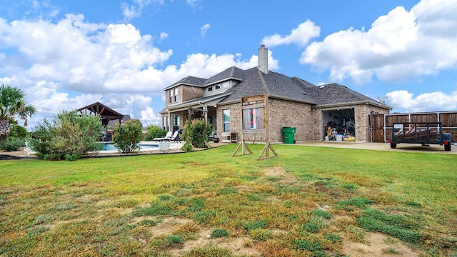 back of property featuring a patio, a pool, and a yard