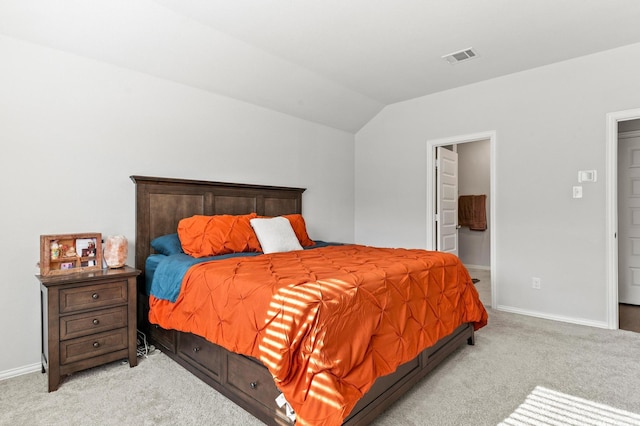 bedroom with connected bathroom, light carpet, and vaulted ceiling