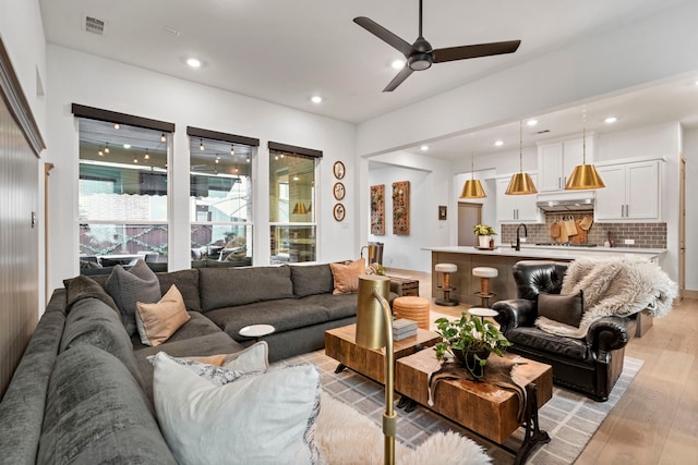 living room featuring light wood-type flooring, ceiling fan, and sink