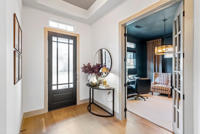 entrance foyer featuring french doors, a tray ceiling, a chandelier, and hardwood / wood-style floors