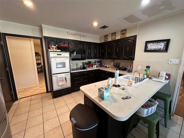 kitchen with light tile patterned flooring, kitchen peninsula, a breakfast bar, and black appliances