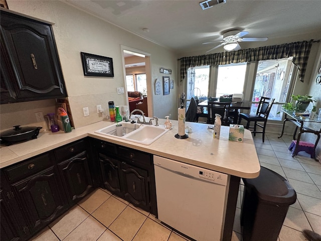 kitchen with light tile patterned floors, kitchen peninsula, ceiling fan, white dishwasher, and sink