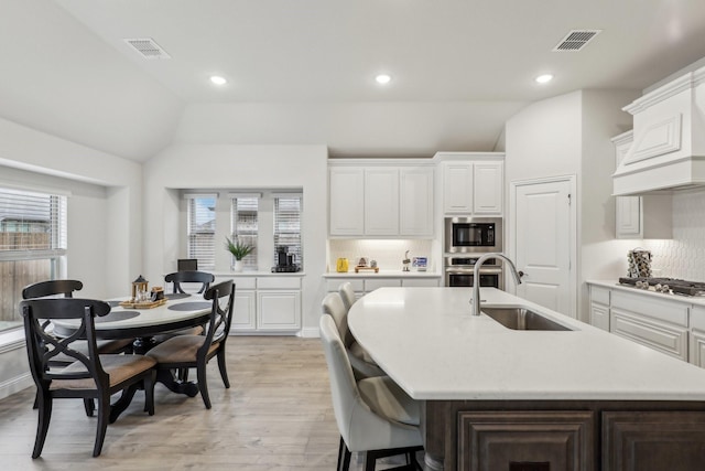 kitchen featuring lofted ceiling, stainless steel appliances, a sink, and visible vents