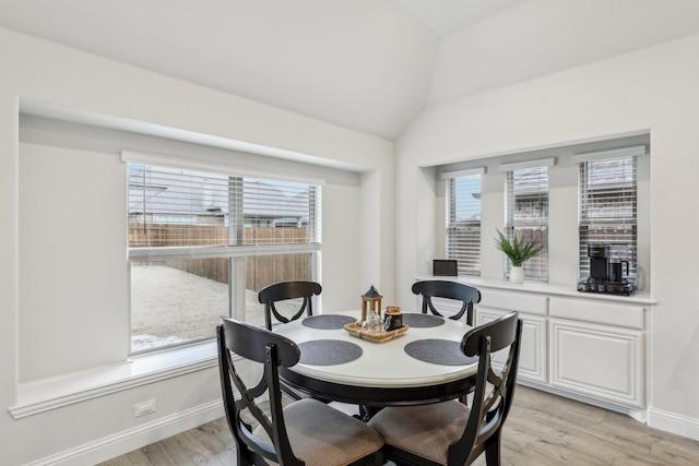 dining room with vaulted ceiling, a wealth of natural light, and light hardwood / wood-style floors