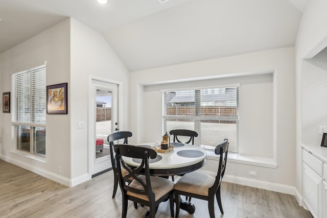 dining space with a wealth of natural light, lofted ceiling, and light wood-type flooring