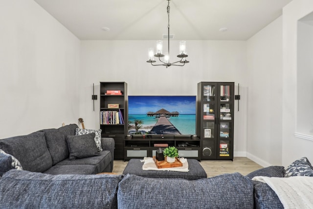 living room featuring visible vents, a notable chandelier, baseboards, and wood finished floors