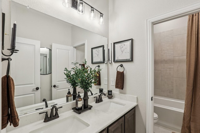 bathroom with double vanity, bathing tub / shower combination, a sink, and toilet