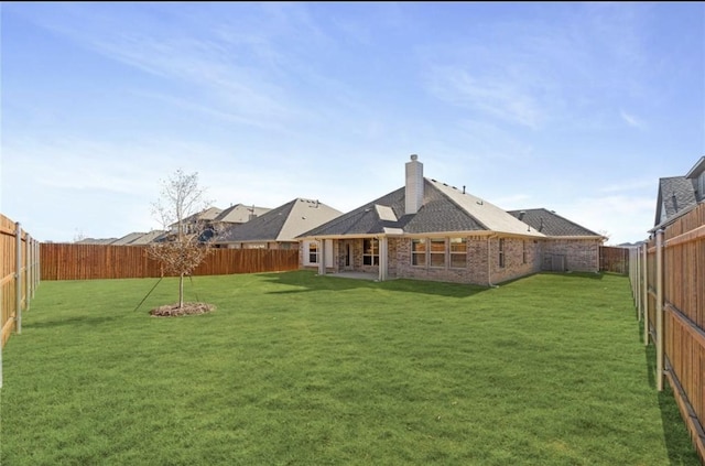 back of property with brick siding, a lawn, and a fenced backyard