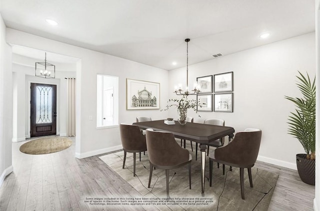 dining space with wood-type flooring and an inviting chandelier