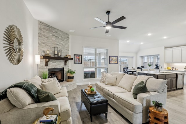 living area featuring a stone fireplace, recessed lighting, light wood-style flooring, and a healthy amount of sunlight