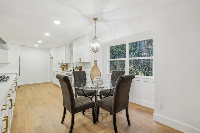 dining area with a notable chandelier, light hardwood / wood-style flooring, and sink