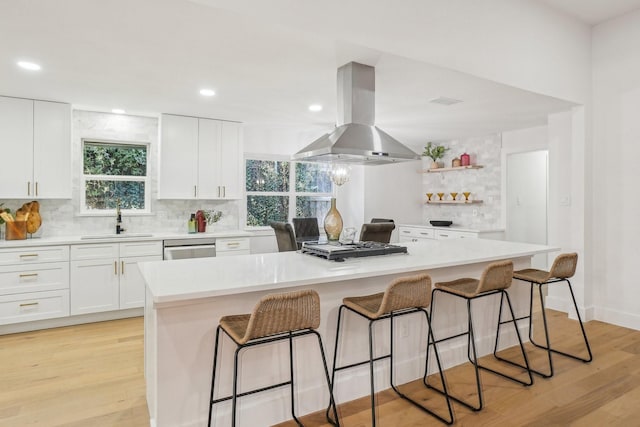 kitchen with island exhaust hood, decorative backsplash, a kitchen island, white cabinets, and sink