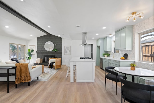 kitchen with island range hood, backsplash, a fireplace, light hardwood / wood-style flooring, and sink