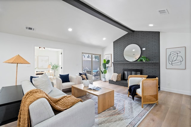 living room with lofted ceiling with beams, a fireplace, and light hardwood / wood-style flooring