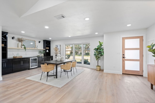 dining space featuring light wood-type flooring and beverage cooler