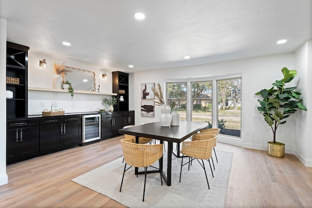 dining room with wine cooler, bar area, and light hardwood / wood-style flooring