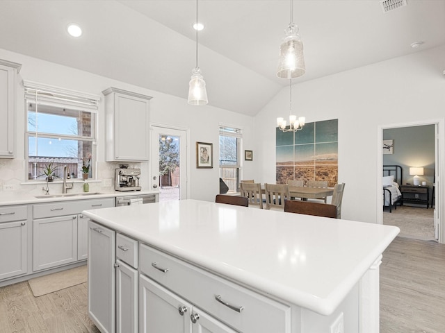 kitchen with a center island, lofted ceiling, decorative light fixtures, sink, and backsplash