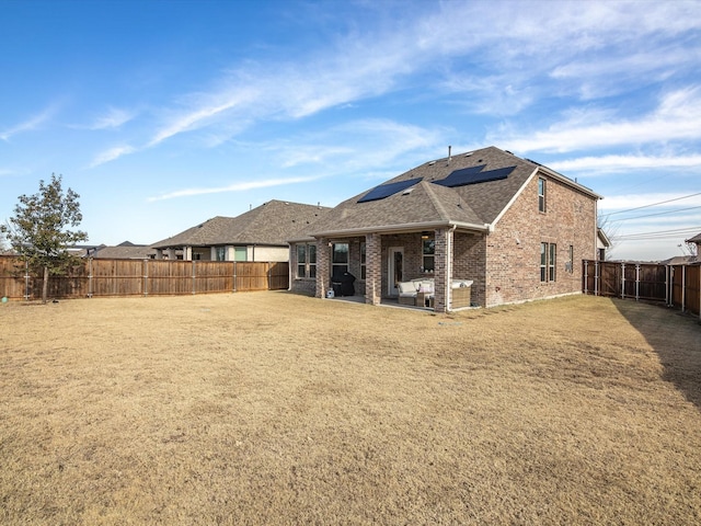 back of house featuring a yard, solar panels, and a patio