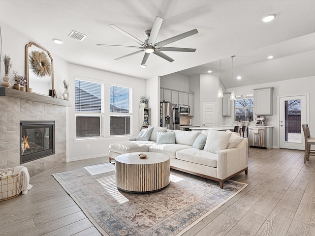 living room featuring ceiling fan and a tiled fireplace