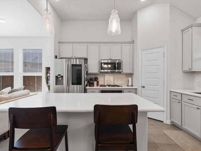 kitchen featuring decorative light fixtures, a kitchen breakfast bar, appliances with stainless steel finishes, and tasteful backsplash