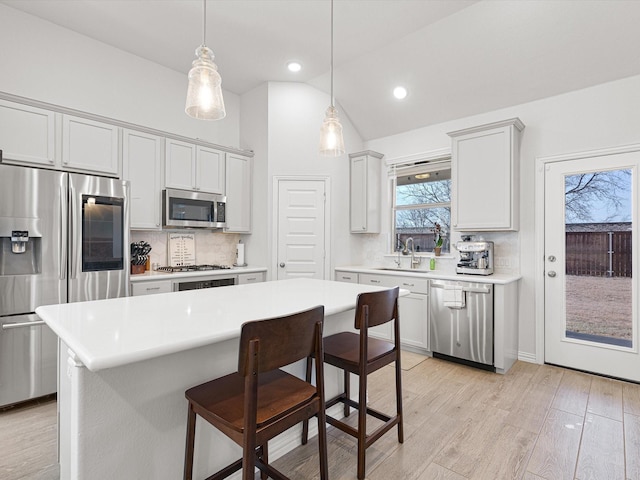 kitchen featuring stainless steel appliances, backsplash, lofted ceiling, pendant lighting, and a center island